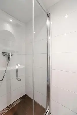 a shower with a glass door in a bathroom at Papillon flat in Zandvoort