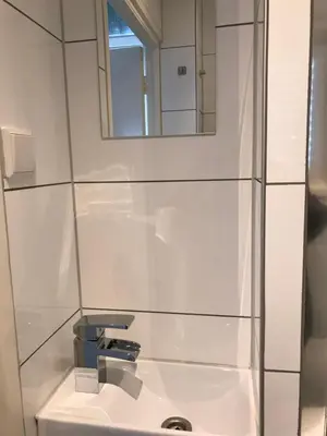a white bathroom with a sink and a mirror at Papillon flat in Zandvoort