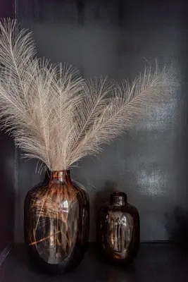 two vases with feathers in them sitting on a table at Papillon flat in Zandvoort
