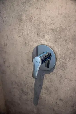 a faucet hanging on a wall with its reflection at Shelter City Christian Hostel in Amsterdam
