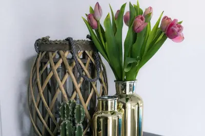 a vase filled with pink tulips sitting next to two bottles at Strandzand in Noordwijk aan Zee