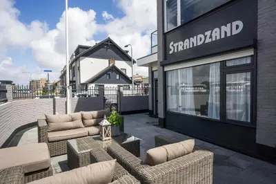 a patio with couches and chairs in front of a building at Strandzand in Noordwijk aan Zee