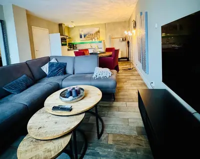 a living room with a blue couch and a table at Strandzand in Noordwijk aan Zee