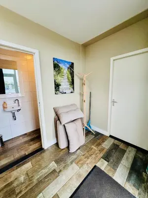 a living room with a chair and a door at Strandzand in Noordwijk aan Zee