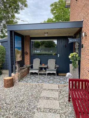 a shed with two chairs and a table in it at Appartement Bos en Duin in Vogelenzang