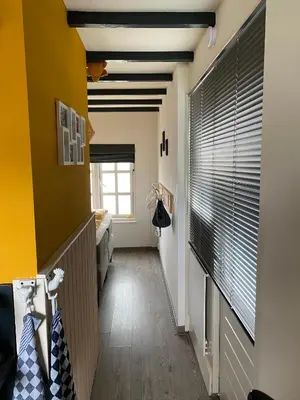 a hallway with a yellow wall and a window at Appartement Bos en Duin in Vogelenzang