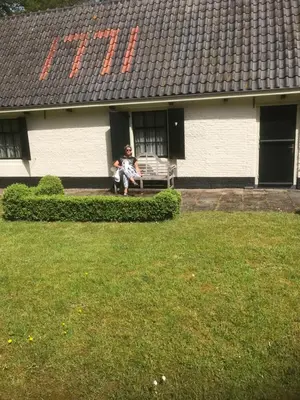 a person sitting on a bench in front of a house at Appartement Bos en Duin in Vogelenzang