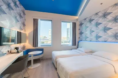 a hotel room with two beds and a desk and two windows at Park Inn by Radisson Amsterdam City West in Amsterdam