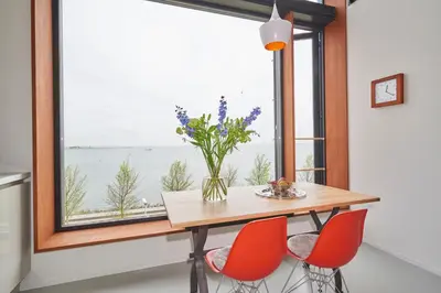 a dining room table with red chairs and a large window at Lake View Apartment Amsterdam in Amsterdam