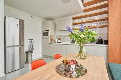 a kitchen with a wooden table with a vase of flowers at Lake View Apartment Amsterdam in Amsterdam