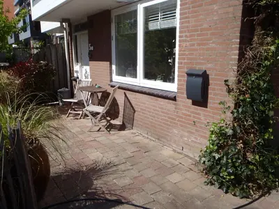 a patio with chairs and a table and a window at Holidaytime in Zandvoort