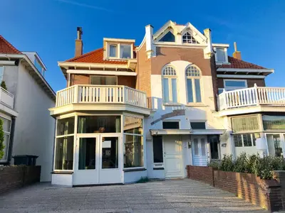 a large brick house with a balcony on a driveway at Maison Rue de la Mer in Zandvoort