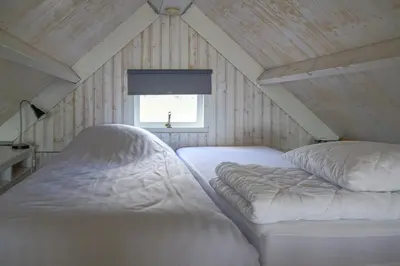 a bedroom with two white beds in a attic at Kusthuisjes in Katwijk