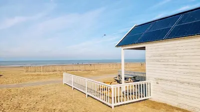 a building with a solar panel on the beach at Kusthuisjes in Katwijk