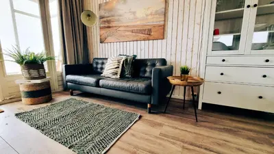 a living room with a leather couch and a rug at Kusthuisjes in Katwijk