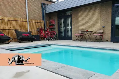 a swimming pool in front of a house with bikes at Paradise Amsterdam bungalow of 80 m2 with private pool - inclusive, parking, use of bikes, tourist tax and much more in Zandvoort