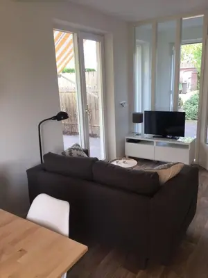 a living room with a black couch and a television at La Tulipe in Egmond aan den Hoef