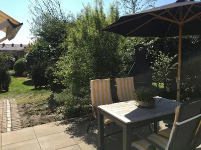 a table and chairs with an umbrella on a patio at La Tulipe in Egmond aan den Hoef