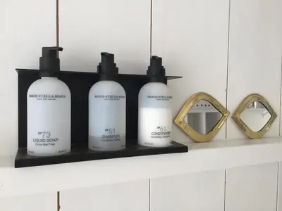 a shelf with three bottles of soap and a mirror at JoyJoyJoy the White Wilde ecolicious studio in a historic Canalhouse from 1799 with terrace at the canals in Amsterdam