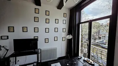 a room with a window with a view of a city at JoyJoyJoy the Black Beauty ecolicious studio in a canal house with French balcony with view on the canals in Amsterdam