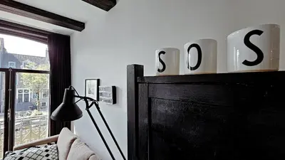 a bedroom with a bed and a sign that says sos at JoyJoyJoy the Black Beauty ecolicious studio in a canal house with French balcony with view on the canals in Amsterdam