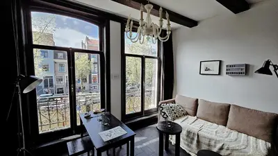 a living room with a couch and some windows at JoyJoyJoy the Black Beauty ecolicious studio in a canal house with French balcony with view on the canals in Amsterdam
