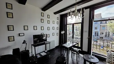 a living room with a table and a large window at JoyJoyJoy the Black Beauty ecolicious studio in a canal house with French balcony with view on the canals in Amsterdam