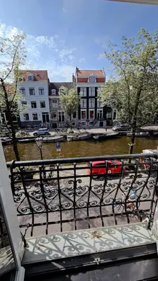 a view of a river with buildings and a red bus at JoyJoyJoy the Black Beauty ecolicious studio in a canal house with French balcony with view on the canals in Amsterdam