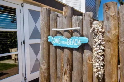 a wooden fence with a sign that reads come home beagle at Aan Zee en Duin in Egmond aan Zee