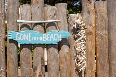 a sign on a fence with a sign going to the beach at Aan Zee en Duin in Egmond aan Zee