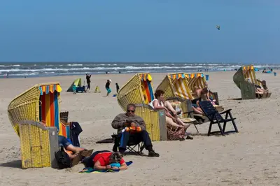 a group of people sitting in lawn chairs on the beach at Aan Zee en Duin in Egmond aan Zee