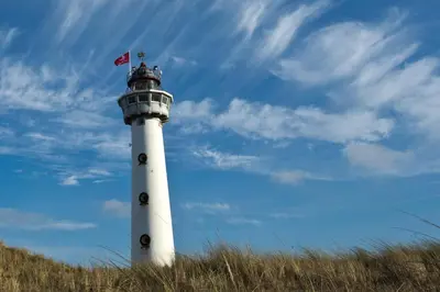 a white lighthouse with a flag on top of it at Aan Zee en Duin in Egmond aan Zee