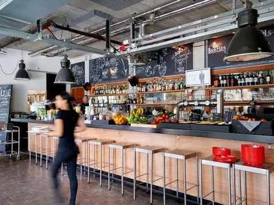 a man walking past a bar in a restaurant at Q-Factory Hotel in Amsterdam