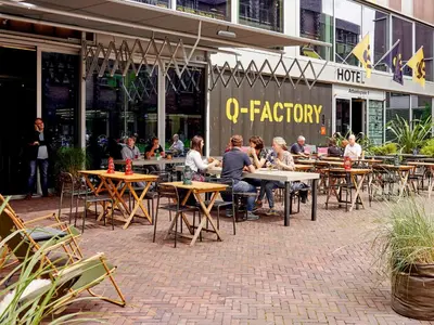 a group of people sitting at tables outside a restaurant at Q-Factory Hotel in Amsterdam