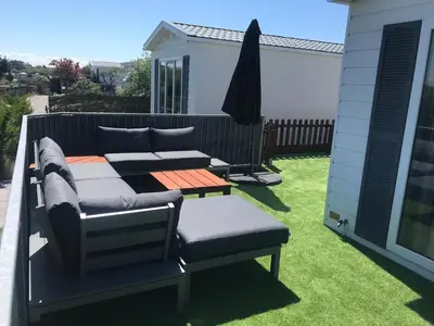 a balcony with a bed and a bench on a lawn at Zee en duin in IJmuiden