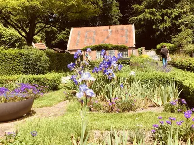 a garden with flowers and a house in the background at Art+bed and breakfast in 's-Graveland