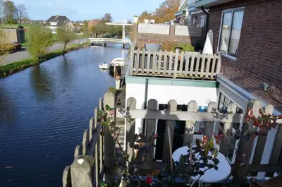 a house with a balcony and a river with a boat at Art+bed and breakfast in 's-Graveland
