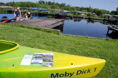 a yellow boat sitting on the grass next to a body of water at Art+bed and breakfast in 's-Graveland