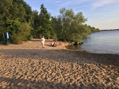 a group of people sitting on a beach near the water at Art+bed and breakfast in 's-Graveland