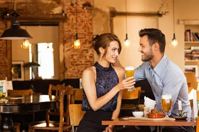 a man and a woman sitting at a table drinking beer at The Highland House in Amsterdam