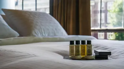 three bottles of essential oils sitting on a bed at Hotel Frank since 1666 in Amsterdam