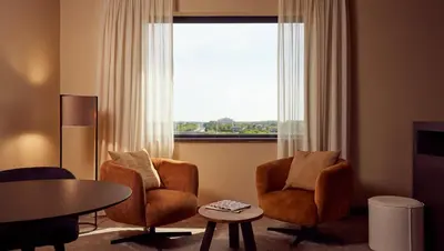 a living room with two chairs and a table and a window at Van der Valk Hotel Amersfoort-A1 in Amersfoort