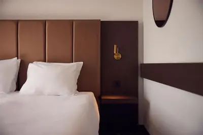 a bed with white sheets and a headboard in a room at Van der Valk Hotel Amersfoort-A1 in Amersfoort