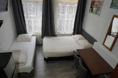 a small room with two beds and two windows at Hotel Schroder in Amsterdam