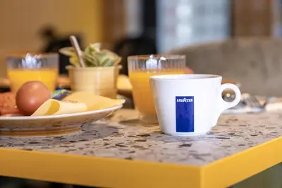 a coffee cup on a table with a plate of food at Tourist Inn One Amsterdam in Amsterdam