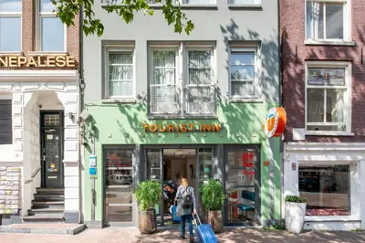 a woman walking down a street in front of a store at Tourist Inn One Amsterdam in Amsterdam