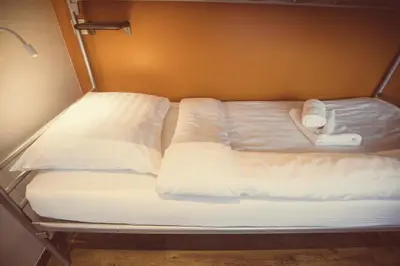 a bed with white sheets and two towels on it at Tourist Inn One Amsterdam in Amsterdam