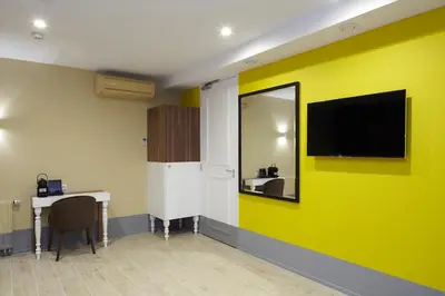 a room with a yellow wall with a desk and a tv at The Muse Amsterdam - Boutique Hotel in Amsterdam