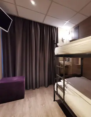 a room with two bunk beds and a purple chair at Hotel Jesse in Amsterdam