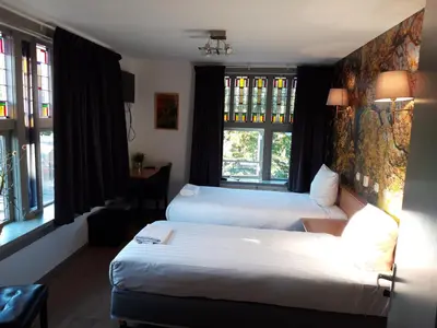a hotel room with two beds and two windows at Hotel Velsen in IJmuiden